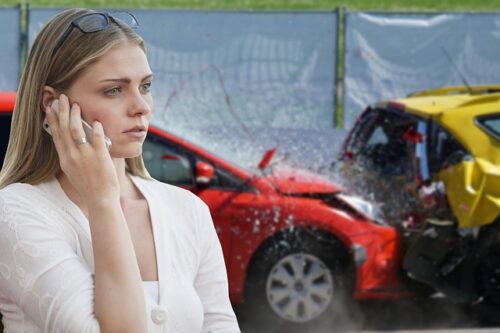 woman on phone in front of car accident