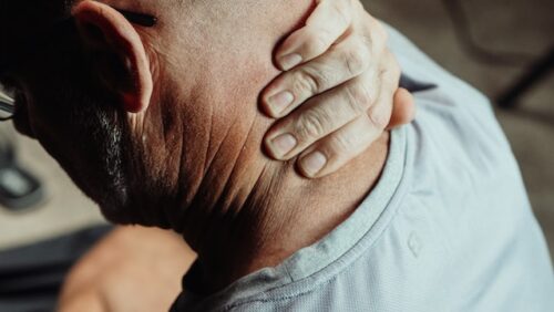 man holding back of neck in pain