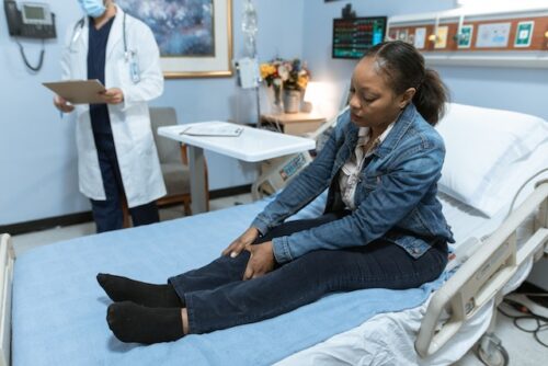 woman holding leg on hospital bed